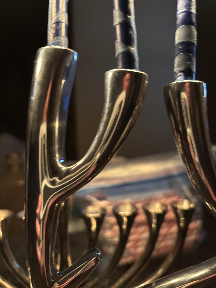 A close-up of a beaten metal menorah with all candles lit